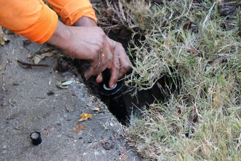 Landscaper performing maintenance on a sprinkler system.