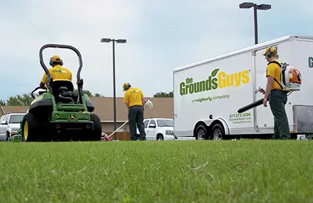 Three Grounds Guys employees performing lawn cleanup work.