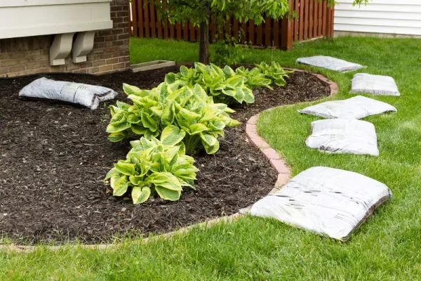 Bags of mulch near a plant bed