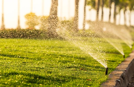 Sprinkler system spraying water on commercial lawn.